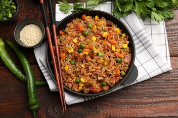 Delicious fried rice in baking dish served on wooden table, flat lay