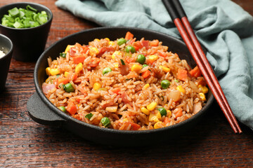 Delicious fried rice in baking dish served on wooden table, closeup