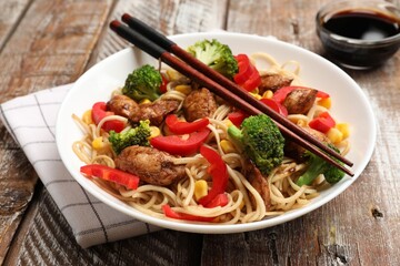 Delicious noodles with meat and vegetables served on wooden table, closeup