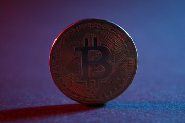 Bitcoin on blue background in red light, closeup