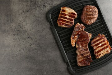 Delicious grilled beef meat on grey table, top view. Space for text