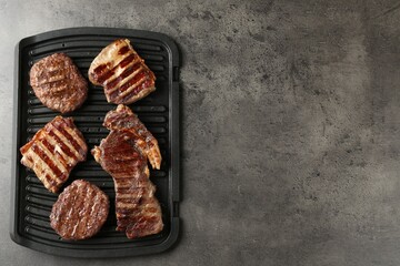 Delicious grilled beef meat on grey table, top view. Space for text