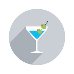 An ice cold turquoise martini glistening in a crisp white glass punctuated with two green olives against a neutral gray