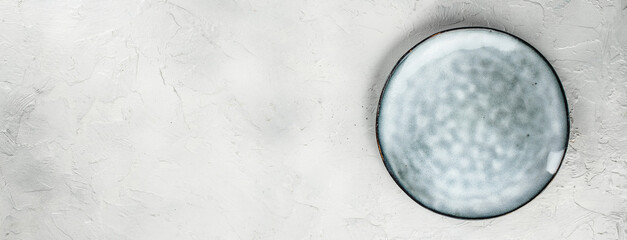 Empty ceramic plate on light textured background, top view, free space for text