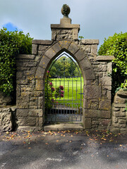 Stone gateway with decorative iron gate and arched top, a historic landmark of tradition and architecture.