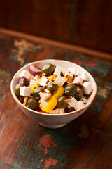 Green and kalamata olives and feta cheese on rustic wooden background. Soft focus.	