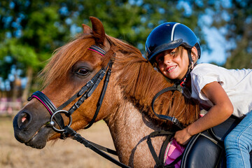 close up portrait of young girl on a horse while horseback riding at sunset in the countryside smiling