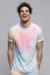 joyful man wearing ultrabright colorful tshirt stands against soft gray background