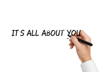 Caucasian hand with white shirt cuff writes "IT'S ALL ABOUT YOU" with a black marker on a bright light grey background with soft bokeh, Concept of customer-centric personalization