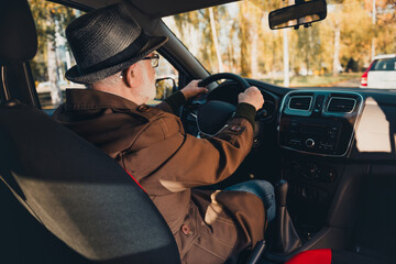 Elderly man drives in autumn sunshine enjoying a leisurely drive in a park surrounded by fall foliage and outdoor beauty