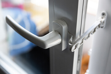 Close-up of a white pvc balcony door handle, an insulating glass window comb fixes the sash....