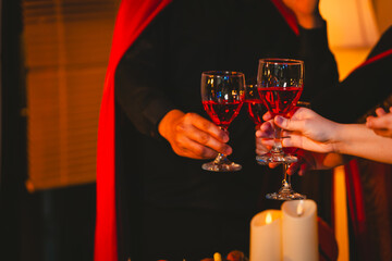 A lively group of friends dressed in Halloween costumes raises their glasses for a toast, celebrating with smiles and laughter at a festive party.