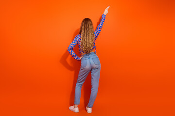 Fashionable young woman posing in colorful attire against a vibrant orange background, showcasing trendy style and contemporary fashion