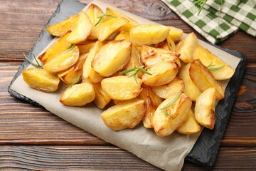 Tasty baked potatoes with rosemary on wooden table, above view
