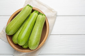 Fresh ripe zucchinis on white wooden table, top view. Space for text