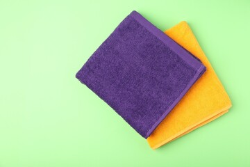 Bright terry towels on green background, top view. Space for text