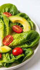 Salad with lettuce halved cherry tomatoes  avocado slices on a lightcolored plate