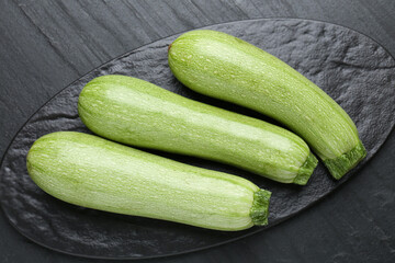 Fresh ripe zucchinis on black textured table, top view