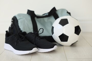 Stylish bag with sports equipment on floor indoors