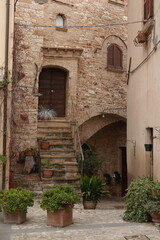 Fototapeta premium Vicolo fiorito e scorcio panoramico a Spello, Umbria: fascino antico e bellezza italiana