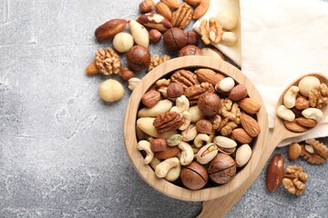 Mix of different nuts on grey textured table, flat lay. Space for text