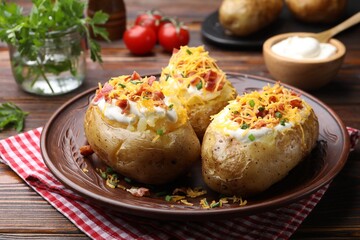 Tasty baked potatoes with sour cream, green onion, cheese and bacon on wooden table, closeup