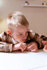 Fototapeta premium A mother and her son with hearing aids share a joyful moment playing board games together. A heartwarming scene of inclusive family bonding, love, and adaptive play