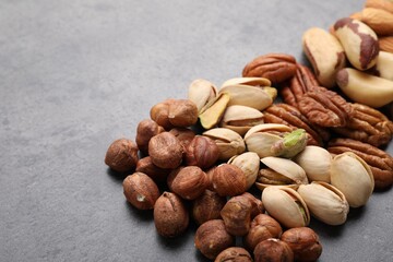 Mix of different nuts on grey table, closeup. Space for text
