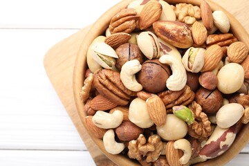 Mix of different nuts in bowl on white wooden table, top view. Space for text