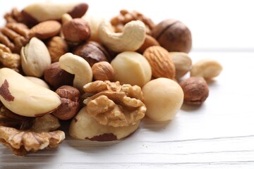 Mix of different nuts on white wooden table, closeup