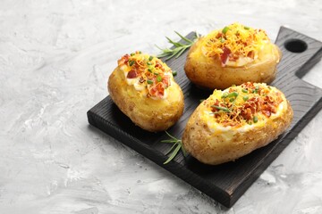 Tasty stuffed baked potatoes on grey textured table, closeup. Space for text