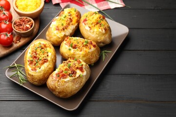 Tasty stuffed baked potatoes on black wooden table, space for text