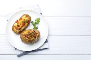 Tasty stuffed baked potatoes on white wooden table, top view. Space for text