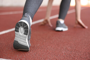 Woman in starting position for run at stadium, closeup