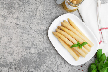 Pickled asparagus, basil and spices on grey table, flat lay. Space for text