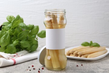 Pickled asparagus, spices and basil on light grey table, closeup