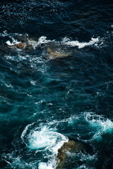 Natural seascape with ocean waves crashing against coastal rocks. The image captures textures of...