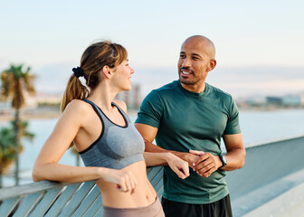 Smiling active young couple jogging exercising and having fun and laughing together taking a break after walking and running in the park, fitness and healhty living concept