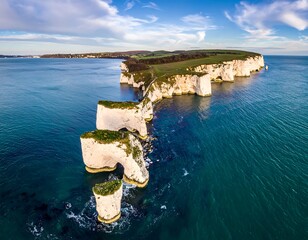 A breathtaking aerial view of dramatic coastal formations, sculpted by the sea, showcasing a beautiful expanse of turquoise water and a vibrant sky.