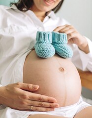 Pregnant woman holding baby booties