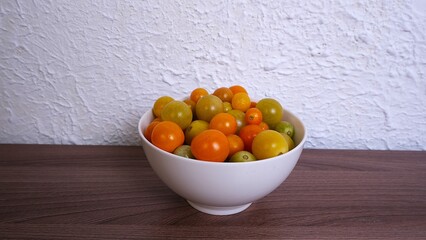 Colorful bowl of fresh cherry tomatoes on wooden table  