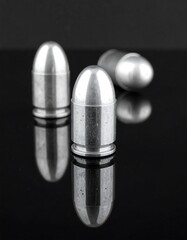 Three metallic bullets on black glass