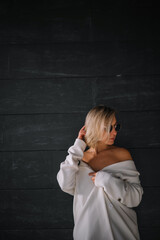 Stylish woman posing against a textured black wall during a sunny day