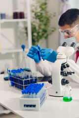 medical or scientific researcher researching and experimenting Multi-colored solution, vial and microscope In the laboratory or in the laboratory by wearing blue gloves and white clothing completely.