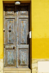 A beautiful old Mediterranean house in a residential district, with its yellow-painted wood door and wall providing security from the sun.