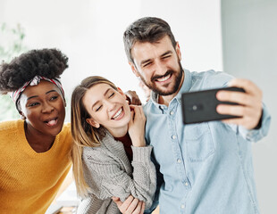 Group of young happy people with mobile phones taking making a selfie photo and having fun together