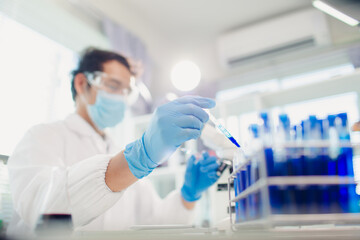 Fototapeta premium medical or scientific researcher researching and experimenting Multi-colored solution, vial and microscope In the laboratory or in the laboratory by wearing blue gloves and white clothing completely.
