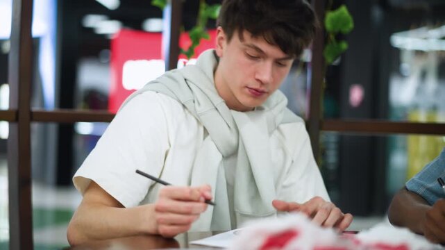 Busy white lad with puffed cheeks exhaling softly during focused drawing session capturing subtle breath motion and gentle rhythm creating calm creative atmosphere under warm indoor lighting