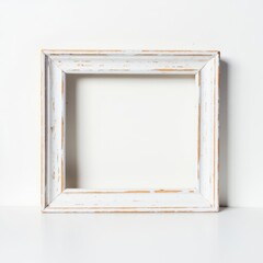 Fototapeta premium Rustic White Wooden Square Frame Mockup. A charming, rustic square photo frame with a distressed white-painted finish, showcasing visible wood grain and scuffed edges. The frame is propped up on a cle