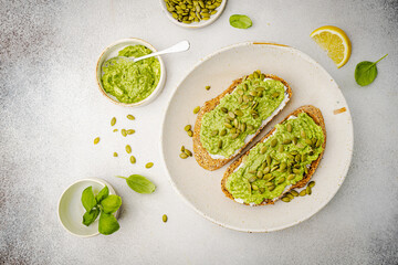 Healthy avocado toast for breakfast or lunch with whole grain bread and pumpkin seeds on a white table. Holistic nutrition concept. Health care, super food concept. top view